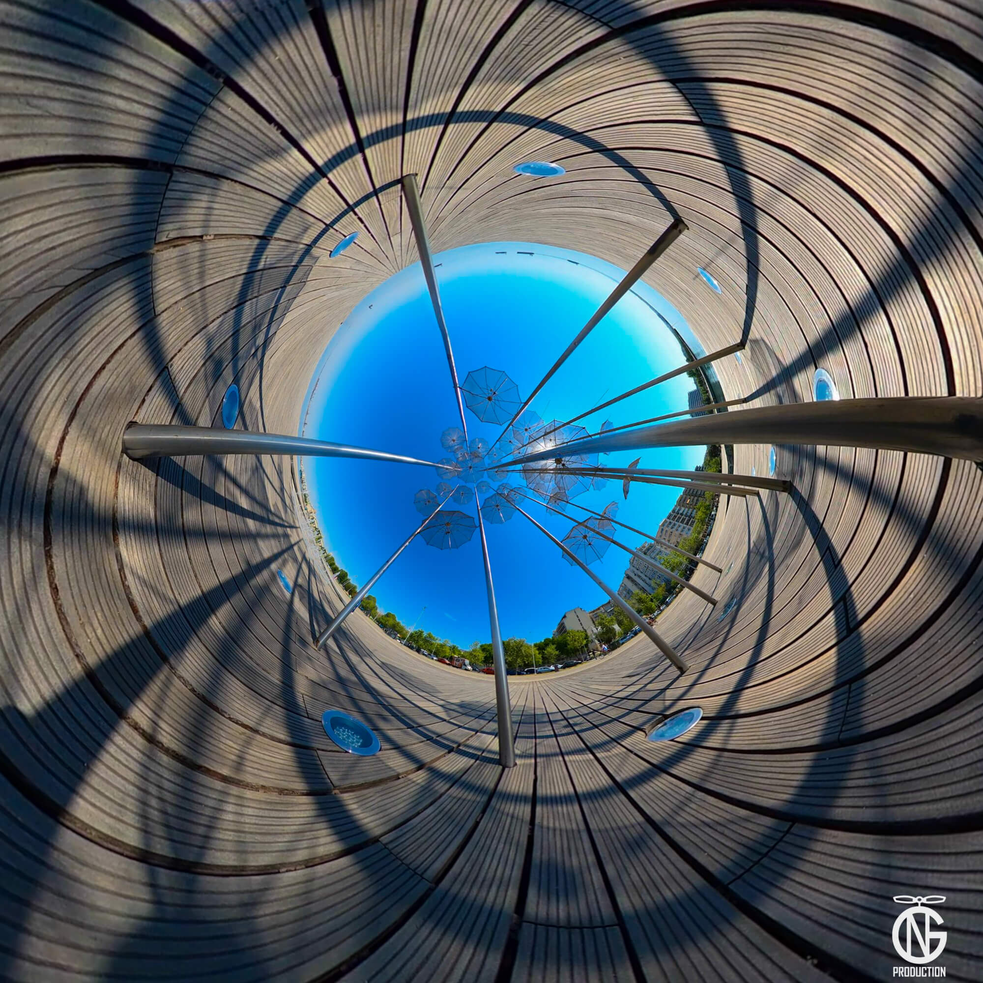 Inverted tiny-planet 360° of Zongolopoulos’ Umbrellas, Nea Paralia Thessaloniki—steel poles, circular shadows, Aegean-blue sky.